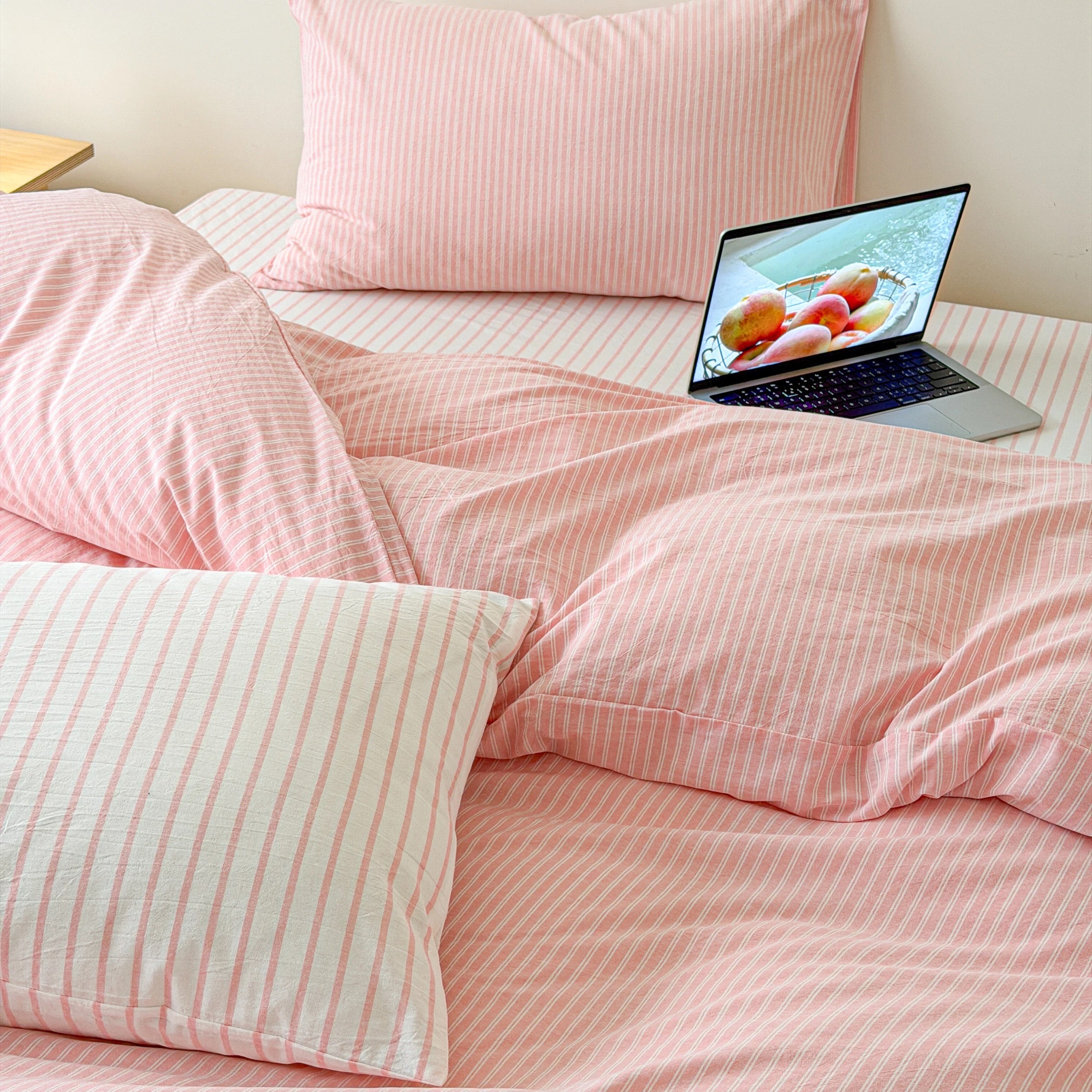 Korean minimal bedroom featuring soft pink striped bedding and bright natural lighting with timeless cotton texture.
