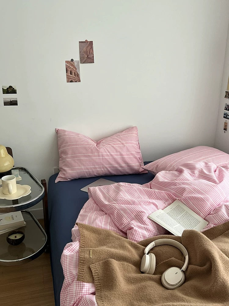 Bedroom with pink checkered bedding and a side table.