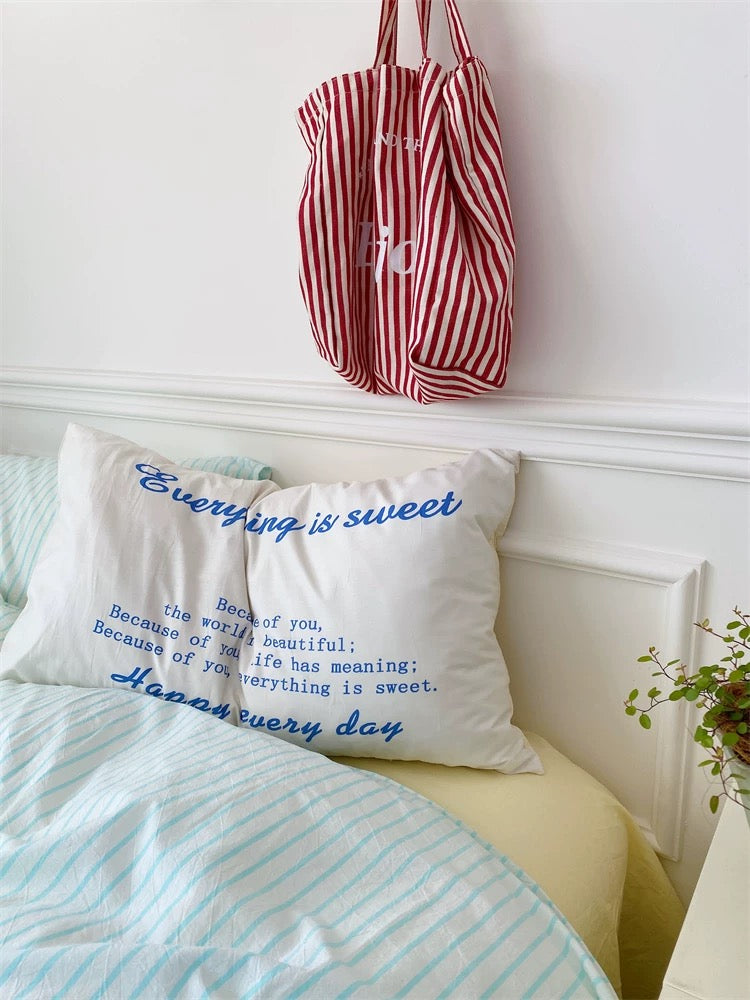 Bedroom with mint green bedding and a red and white striped bag hanging on the wall.
