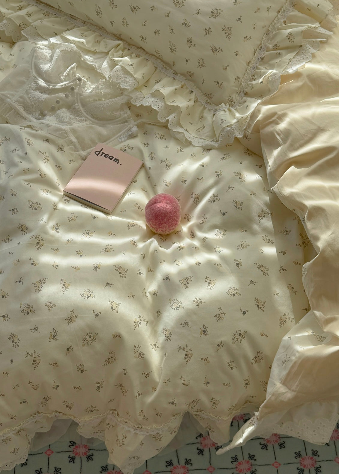 Floral-patterned bedding with a pink book and decorative ball on a bed.