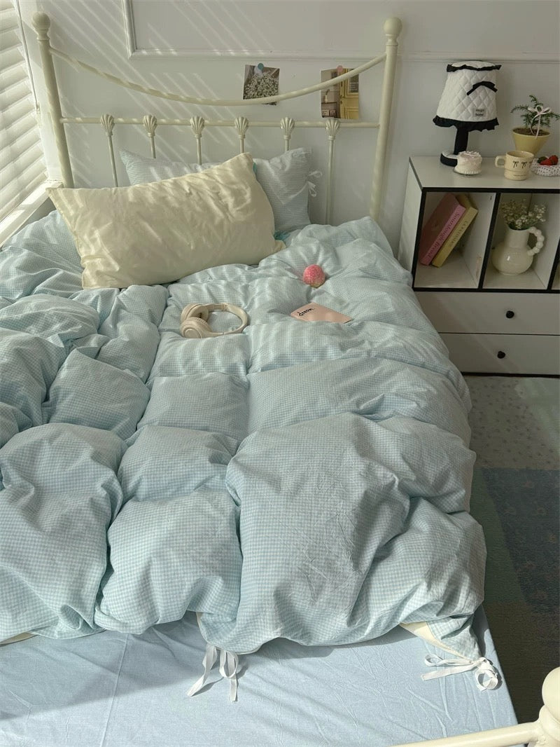 Light blue comforter on a bed with a nightstand in the background