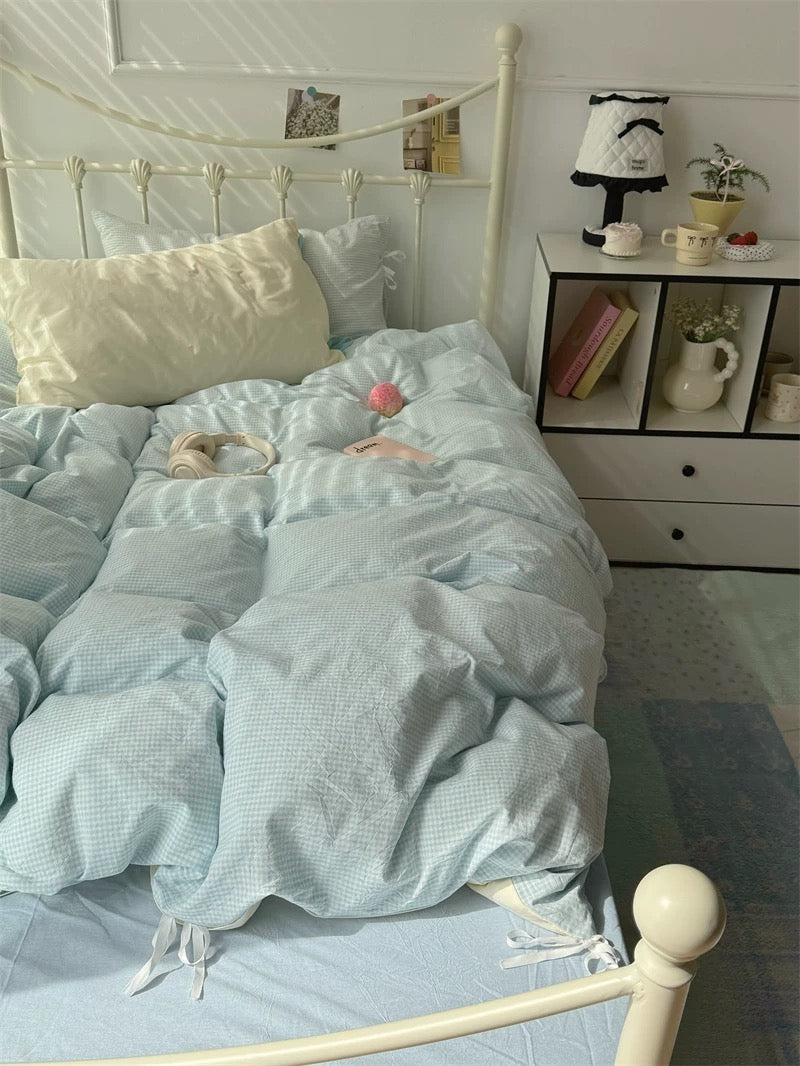 Bed with light blue bedding in a bedroom setting