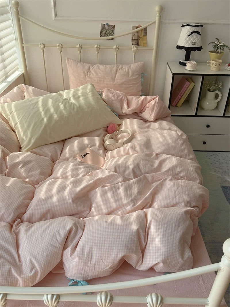Pink bedding on a bed with a white headboard in a room.