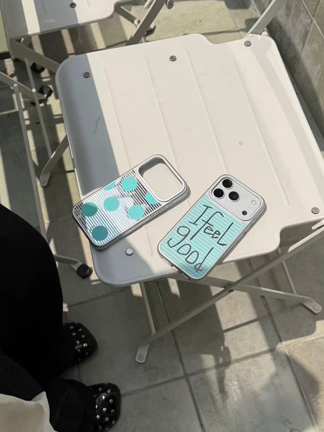 The Feel Good iPhone case hangs beside the aqua polka dot design, showing both patterned backs.