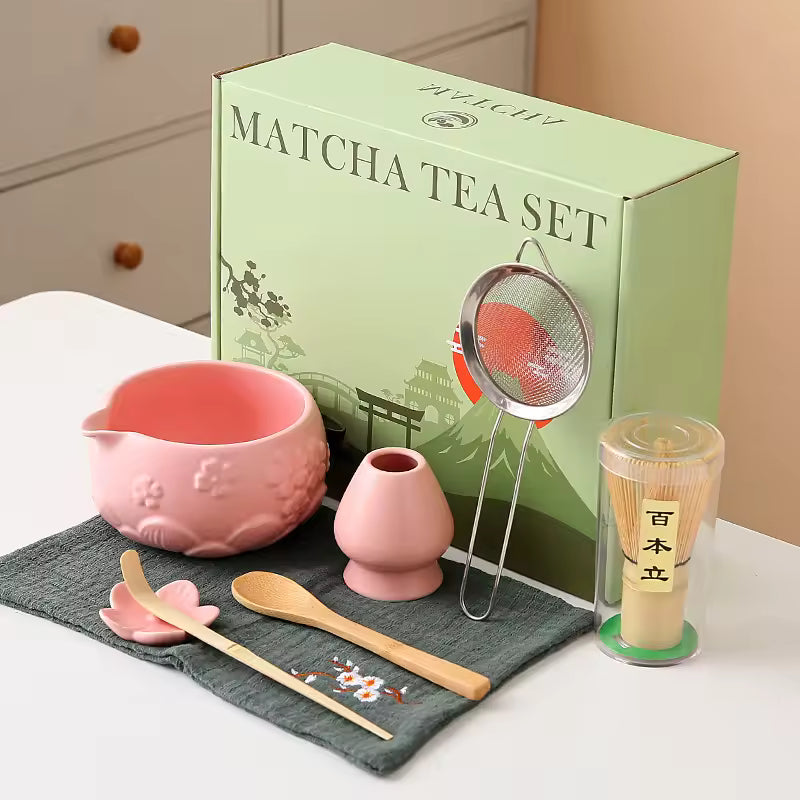 Matcha tea set with pink teapot, whisk, and other tools in front of a green box labeled 'Matcha Tea Set'.