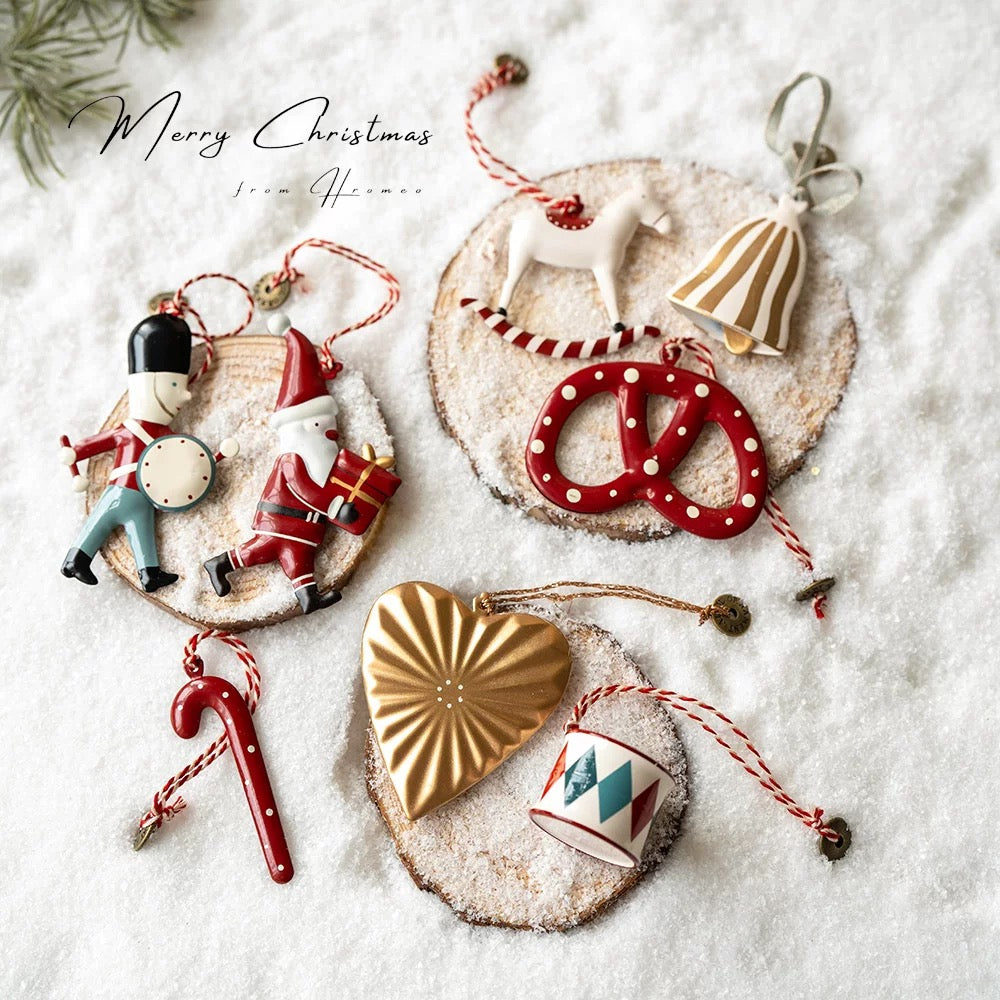 Scandinavian Christmas ornaments show a white angel, red drum, snowman and dotted red pretzel.