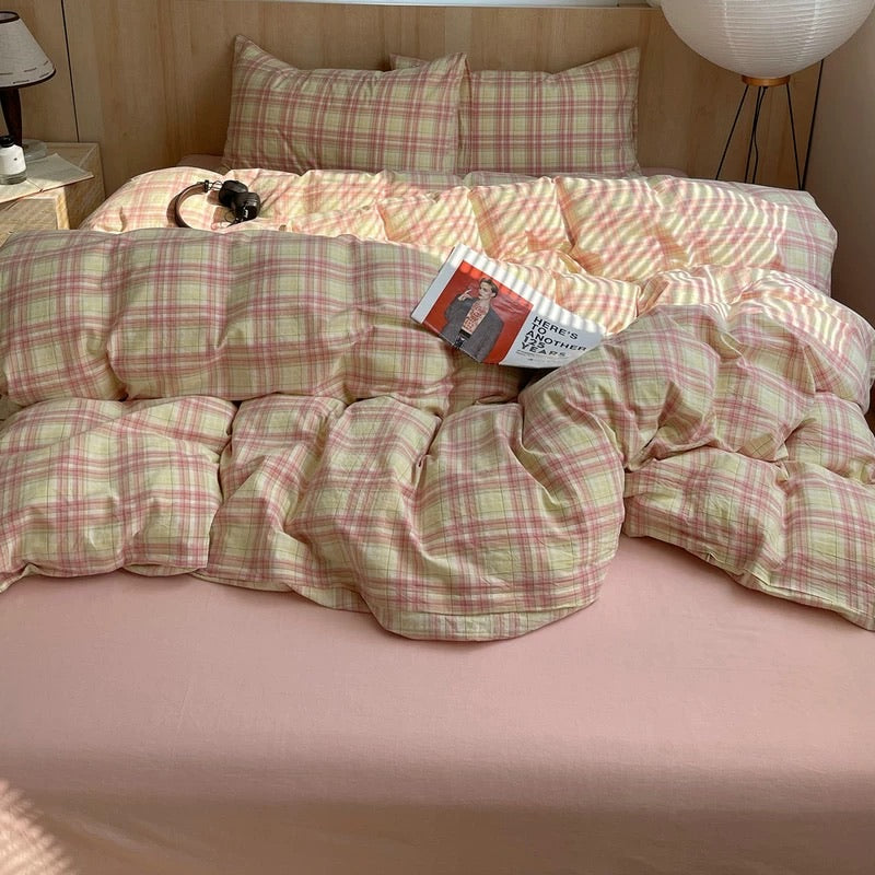 Bed with plaid comforter and pillows in a bedroom setting