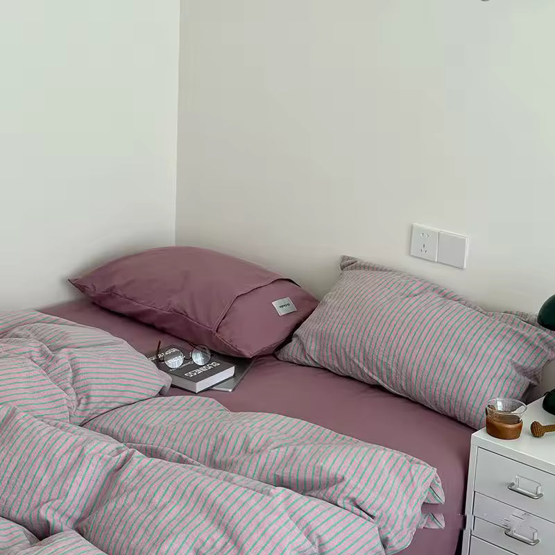 Bed with pink and white striped bedding in a bedroom setting.