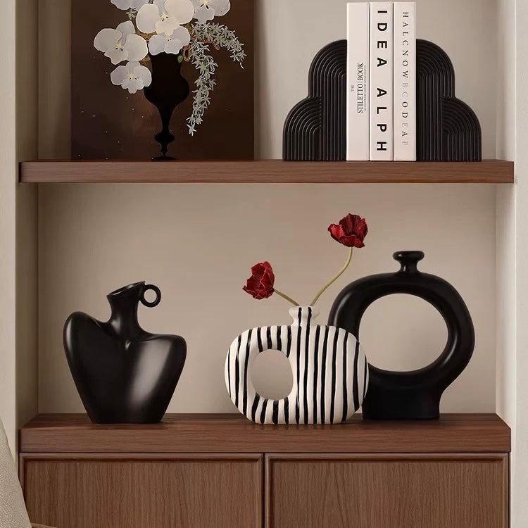 Decorative vases and a striped tray on a wooden shelf with a neutral background
