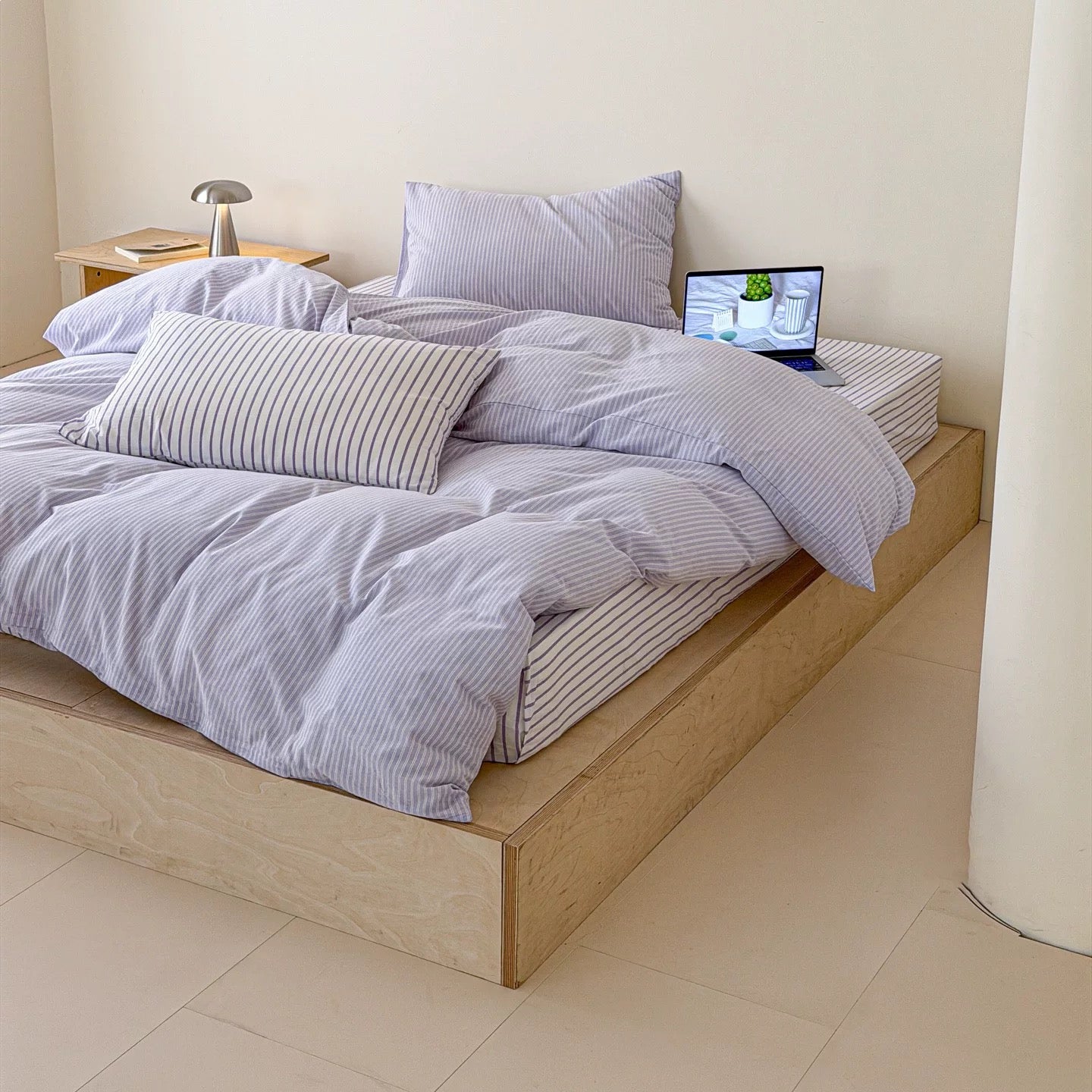 Bed with striped bedding and pillows in a minimalistic room.