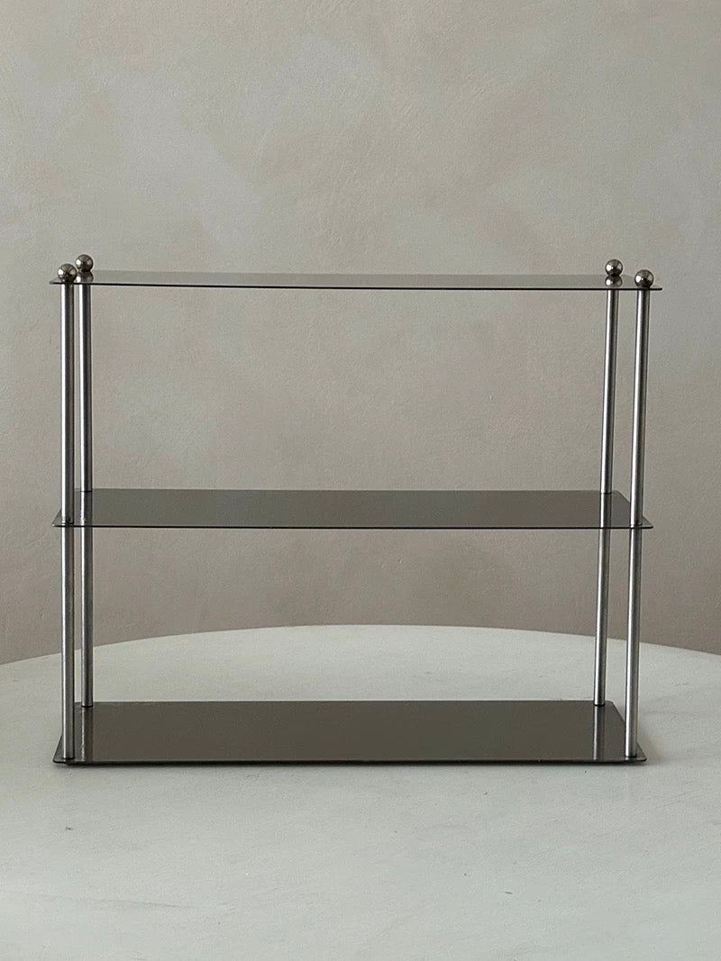 Glass shelf with metal frame on a white surface and light gray background