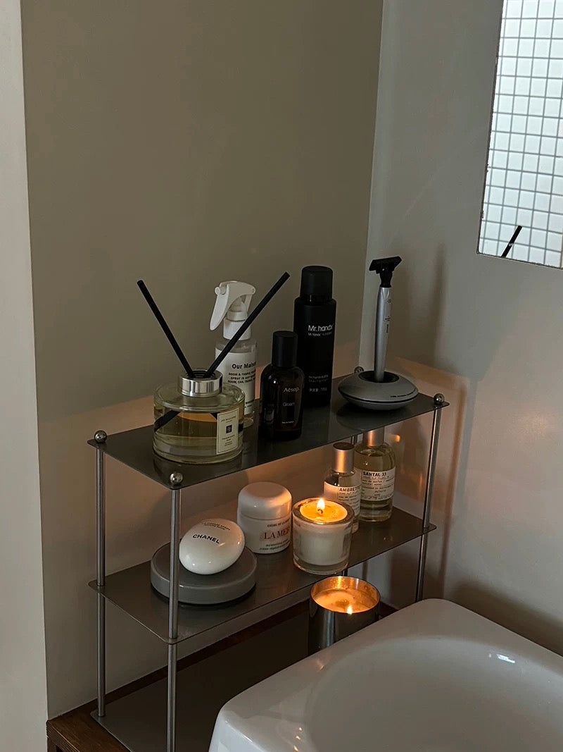 Small shelf with various items including candles and bottles in a bathroom setting.