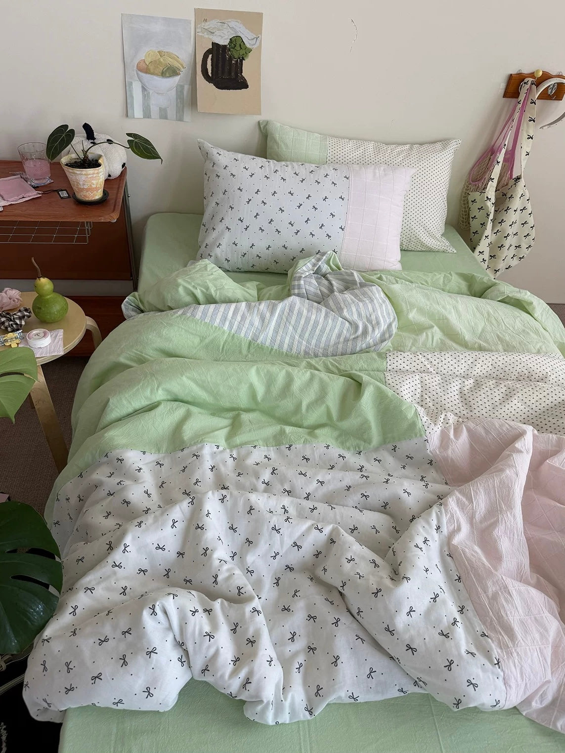 Mint green and pink patchwork bedding on a bed beside a wooden nightstand