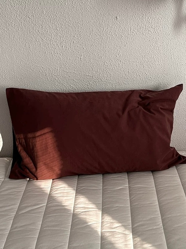 A mocha brown pillowcase with a plain surface and visible folds.