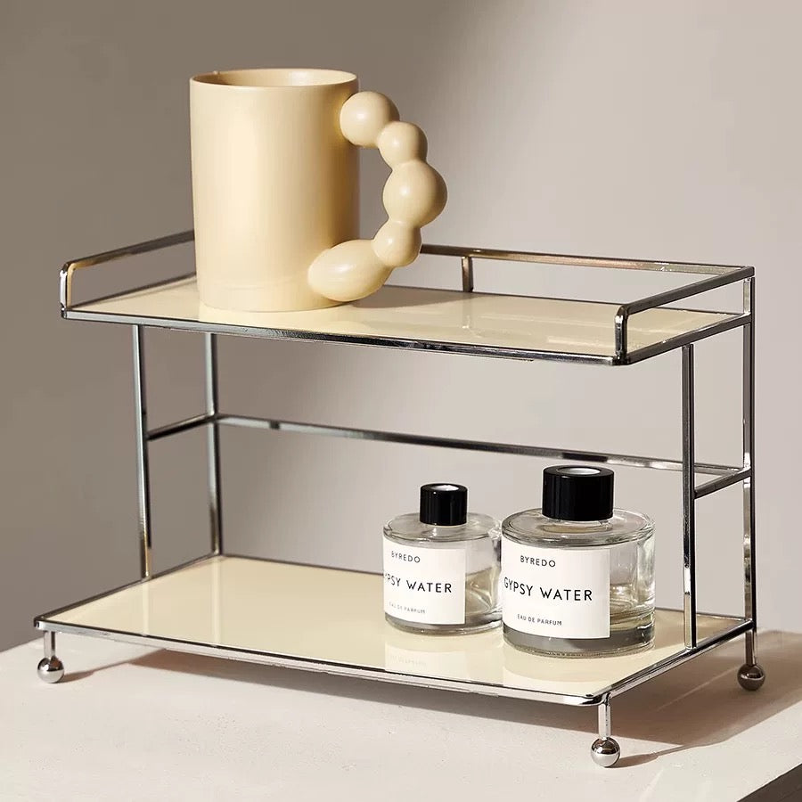 Small bar cart with a large mug and two bottles of Byredo perfume on a neutral background