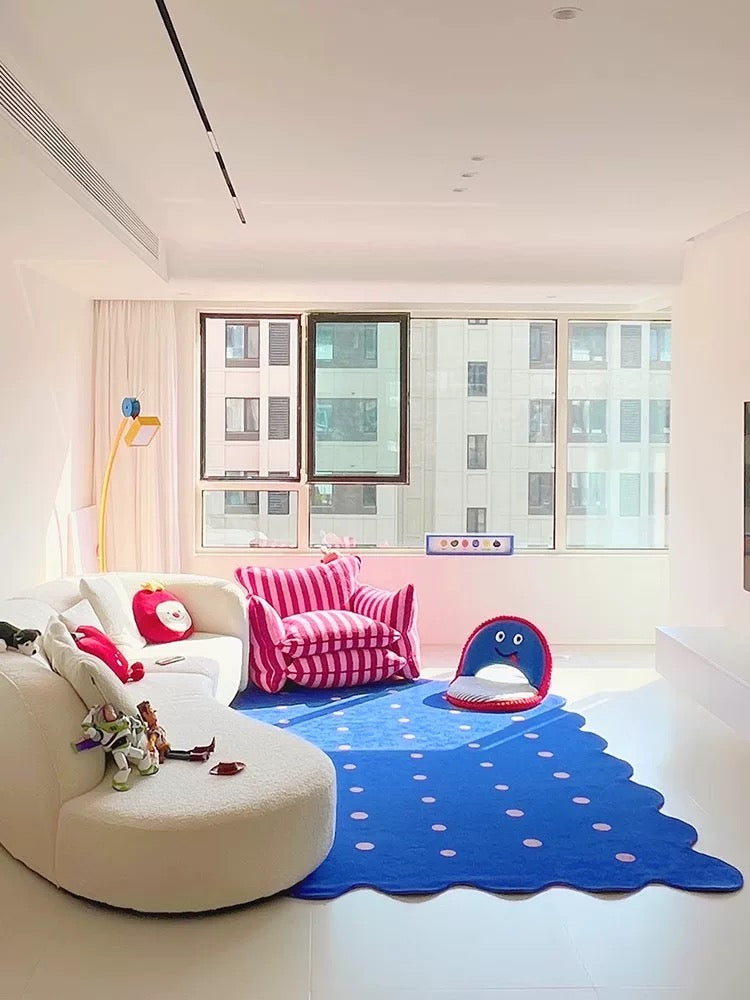 Children's room with a blue polka dot rug, pink striped chair, and colorful toys.