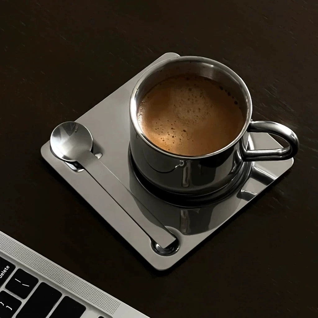 Espresso cup on a metal coaster with a laptop in the foreground