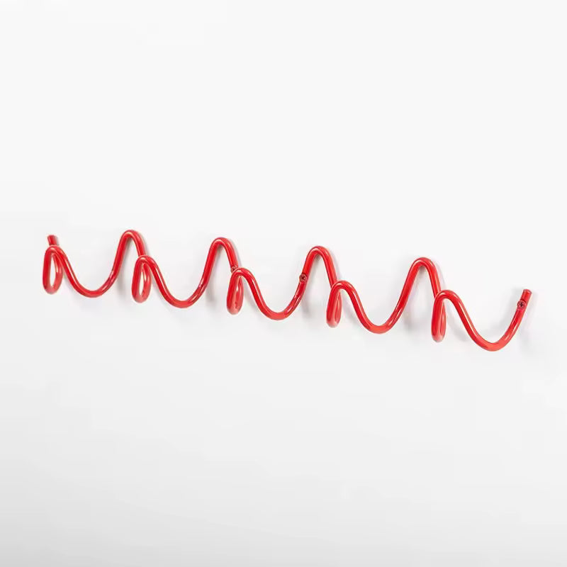Red wavy wall-mounted hook rail used as a creative coat rack for home or dorm rooms.