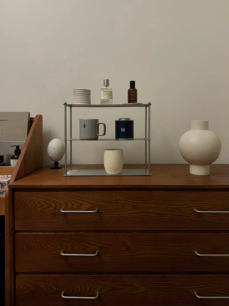 Wooden dresser with a glass shelf holding decorative items against a plain wall.