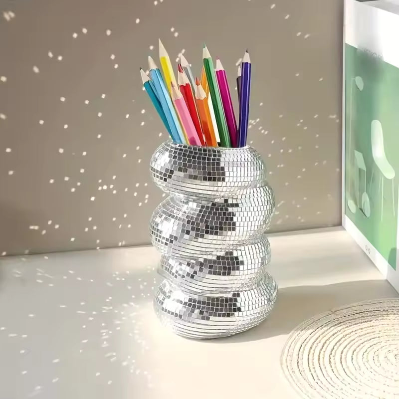 Silver disco ball pencil holder with colorful pencils on a neutral background