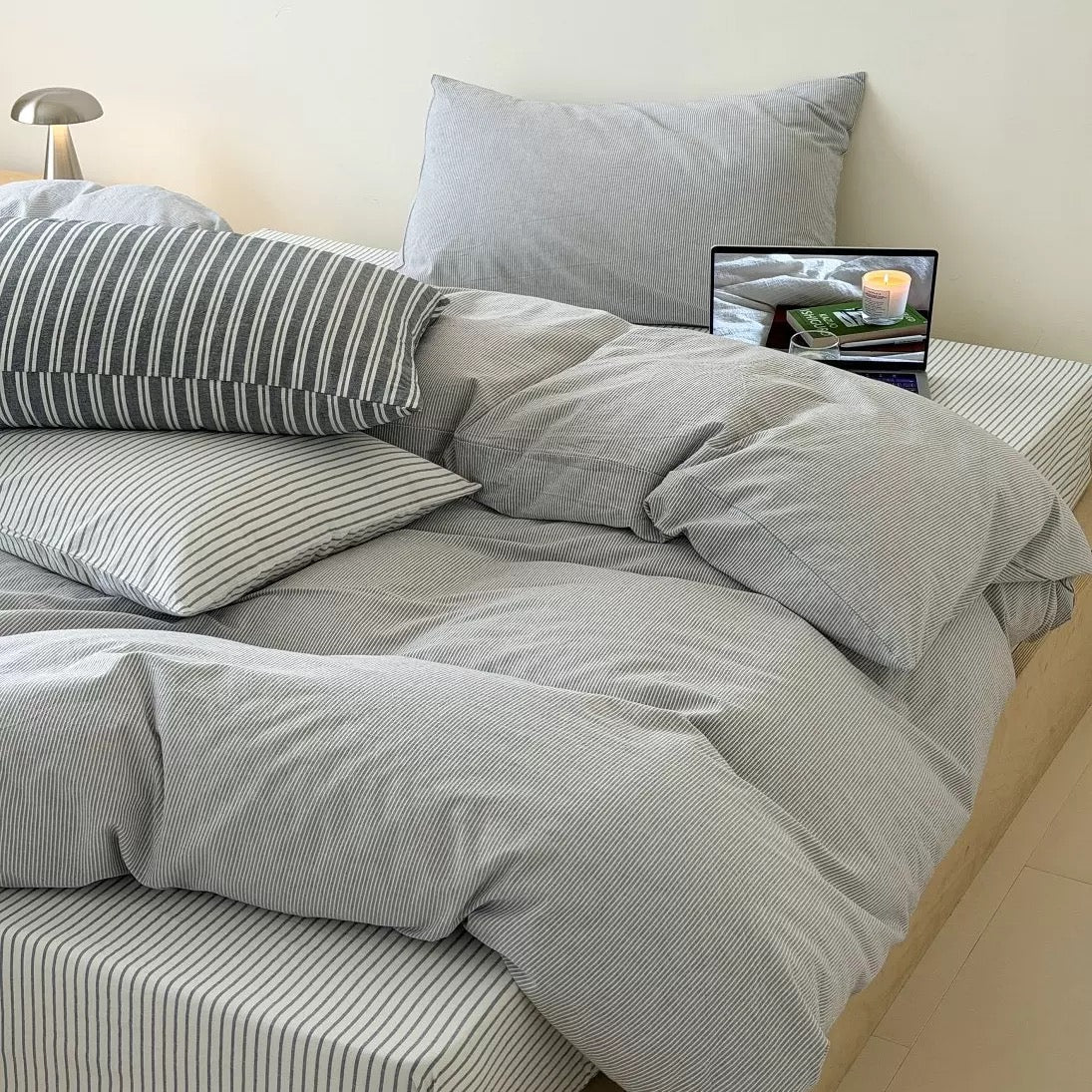 Japandi inspired gray bedding creating peaceful minimalist interior with fine striped cotton texture and soft lighting throughout.
