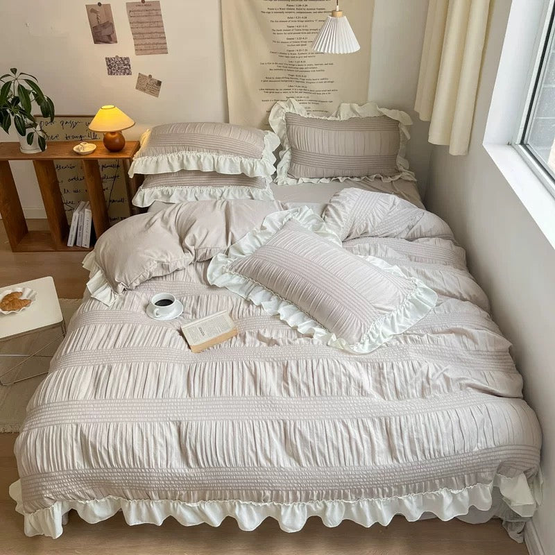 Neatly made bed with ruffled bedding in a cozy bedroom setting.