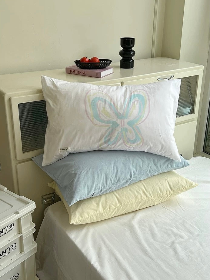 White pillowcase with a pastel butterfly design on a neatly made bed.