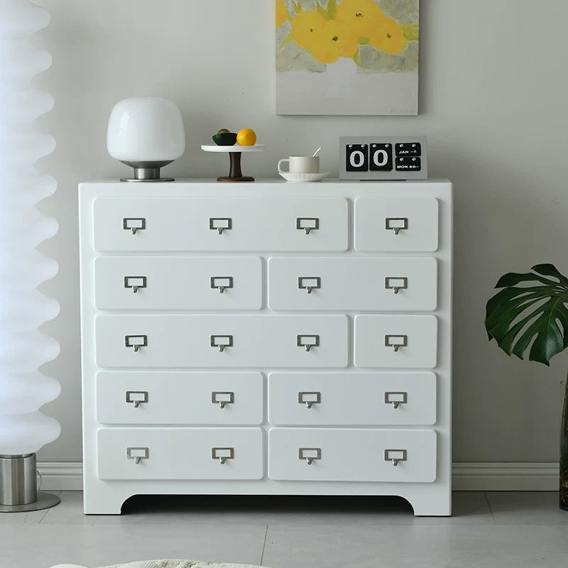 White dresser with decorative items against a gray wall