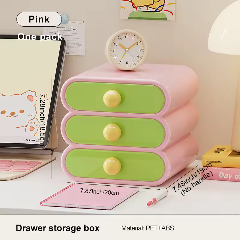 Pink and green drawer storage box on a desk with a clock on top, surrounded by stationery items.