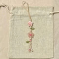 Decorative string with pink flowers and green leaves on a beige fabric background
