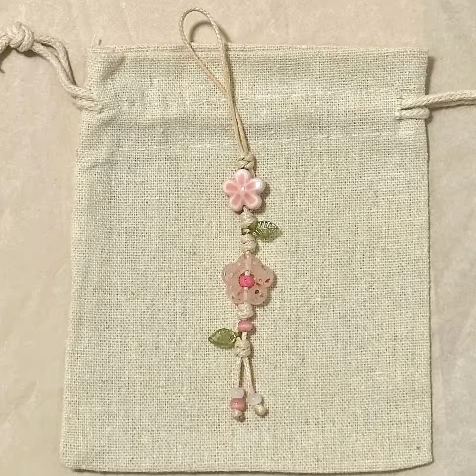 Decorative string with pink flowers and green leaves on a beige fabric background