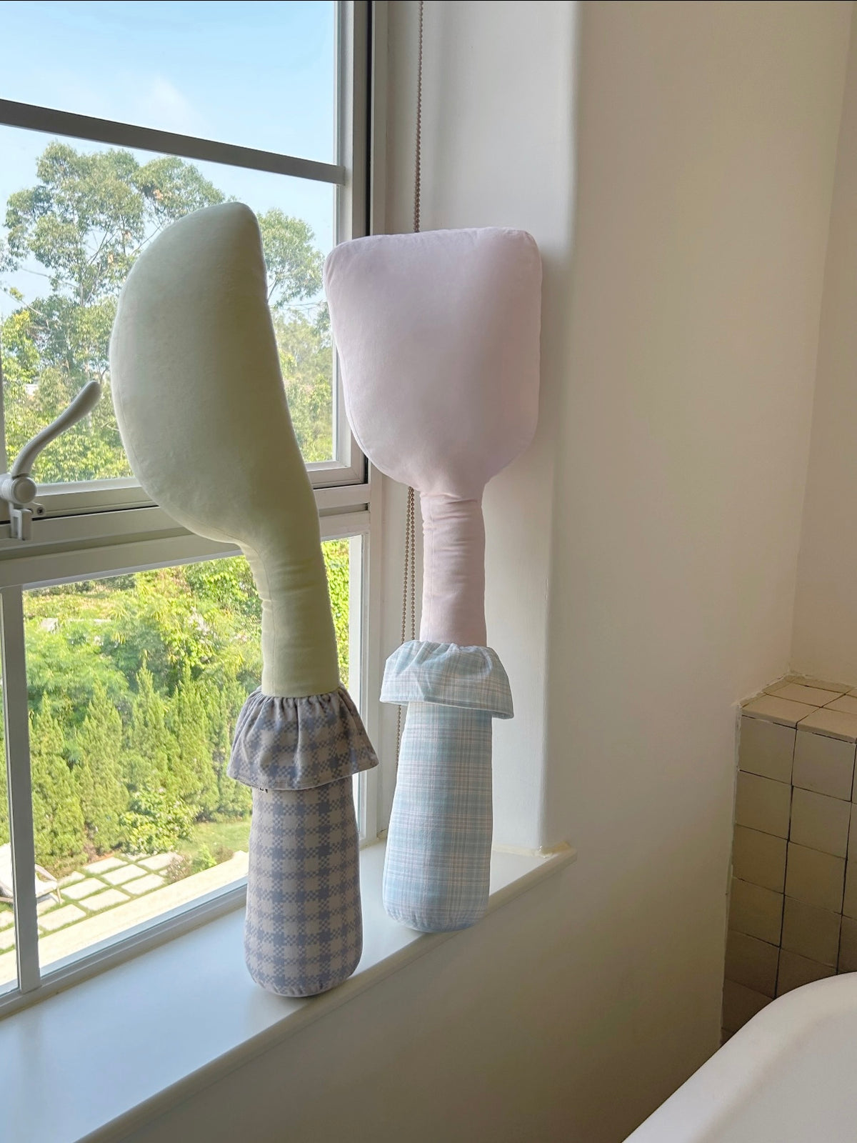 Yellow knife and pink spatula shapes stand upright, with checked handles and fabric collars on each utensil pillow.