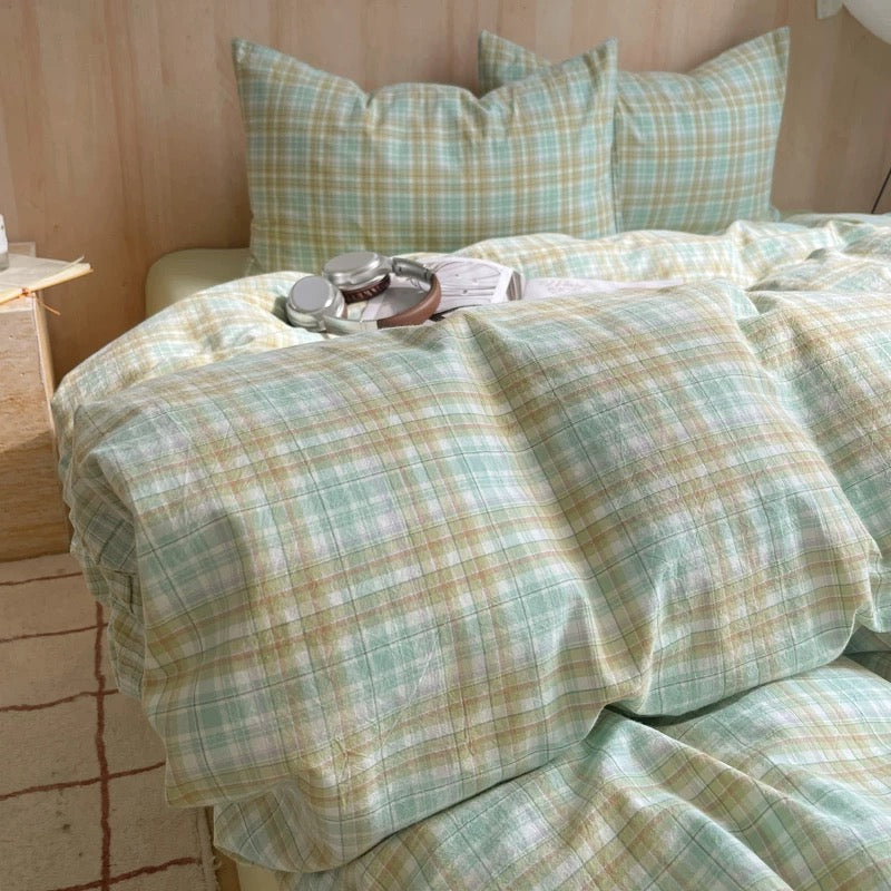 Plaid bedspread on a bed with pillows in a bedroom setting