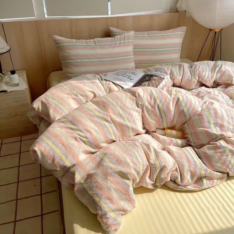 Bed with striped bedding and pillows in a well-lit room.