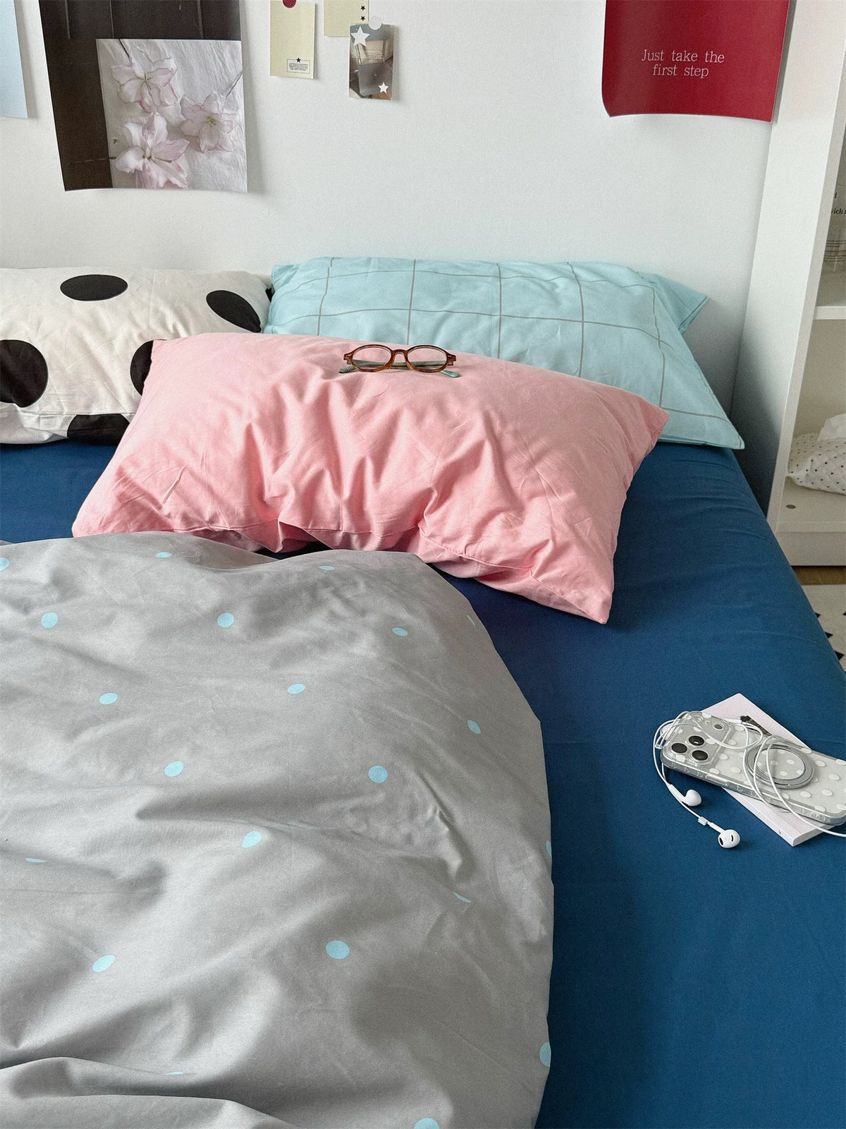 Pink and blue check pillowcases above the gray cover with small blue dots.