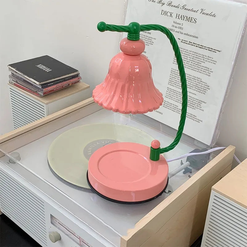 Pink candle warmer lamp with a scalloped shade suspended above a round matching pink base.