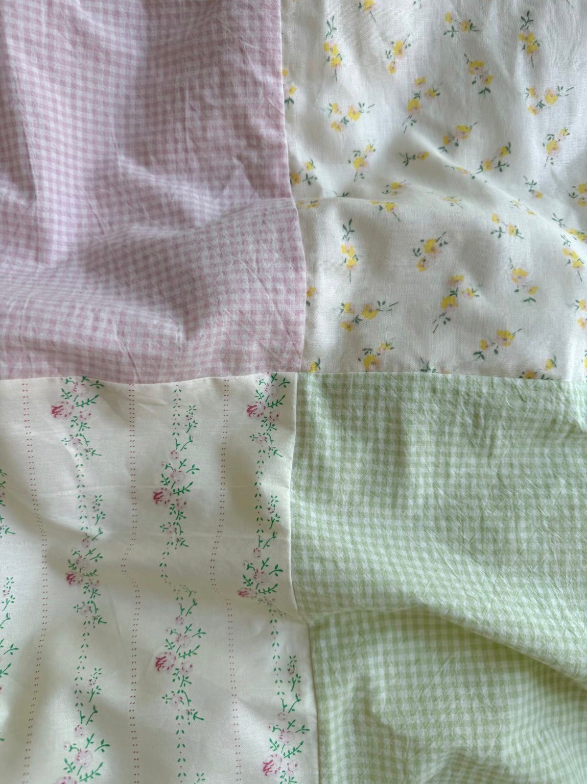 Close-up of pink and green patchwork bedding with floral panels