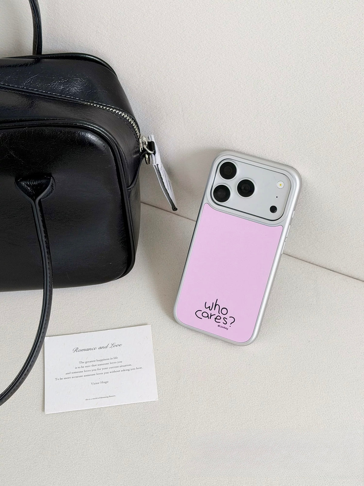 Pink iPhone case resting at an angle, showing its pale back, silver colored border and camera opening.