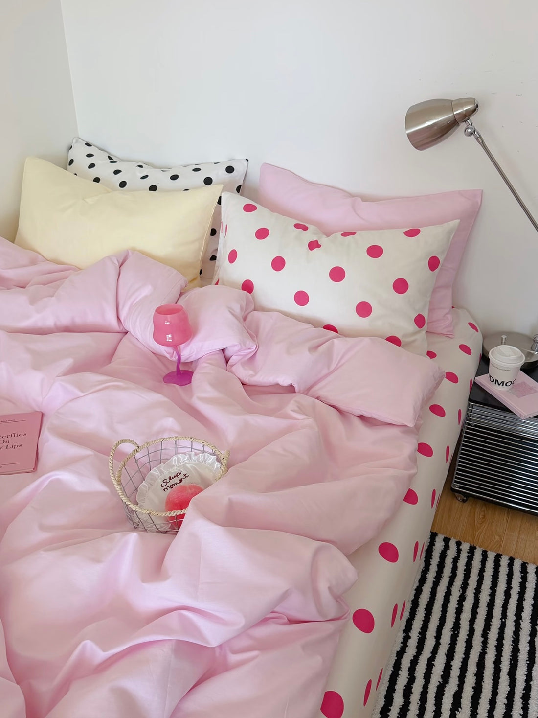 Pink polka dot bedding set with a plain pink cover, yellow and dotted pillows, and a white sheet with fuchsia dots.