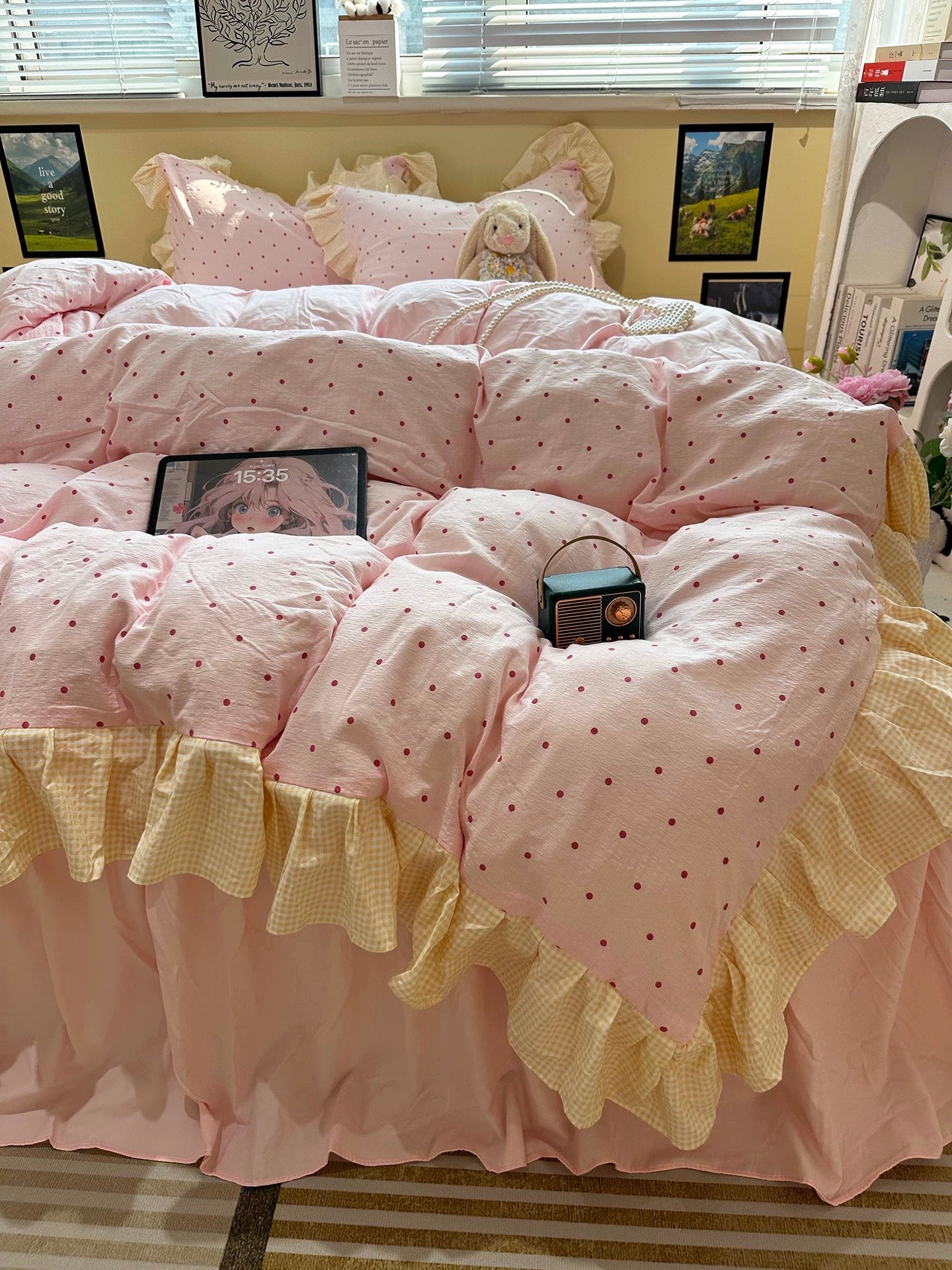 Pink polka dot comforter with ruffle trim on a bed in a room.