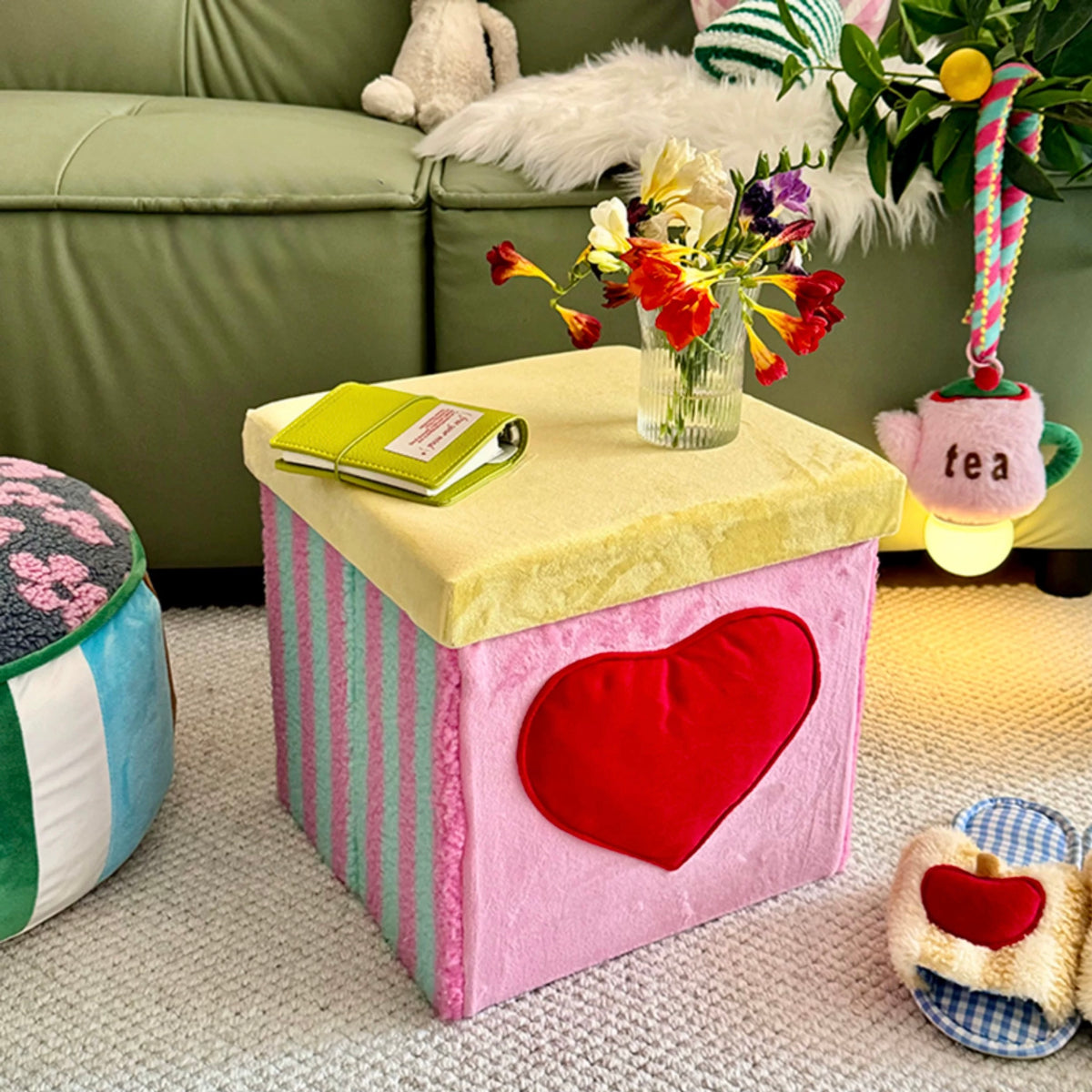 Pink velvet storage stool styled as a side table in a colorful room