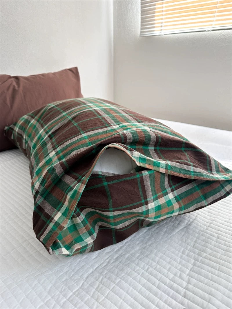 A folded plaid pillowcase shows its brown ground, green bands and fine light lines.
