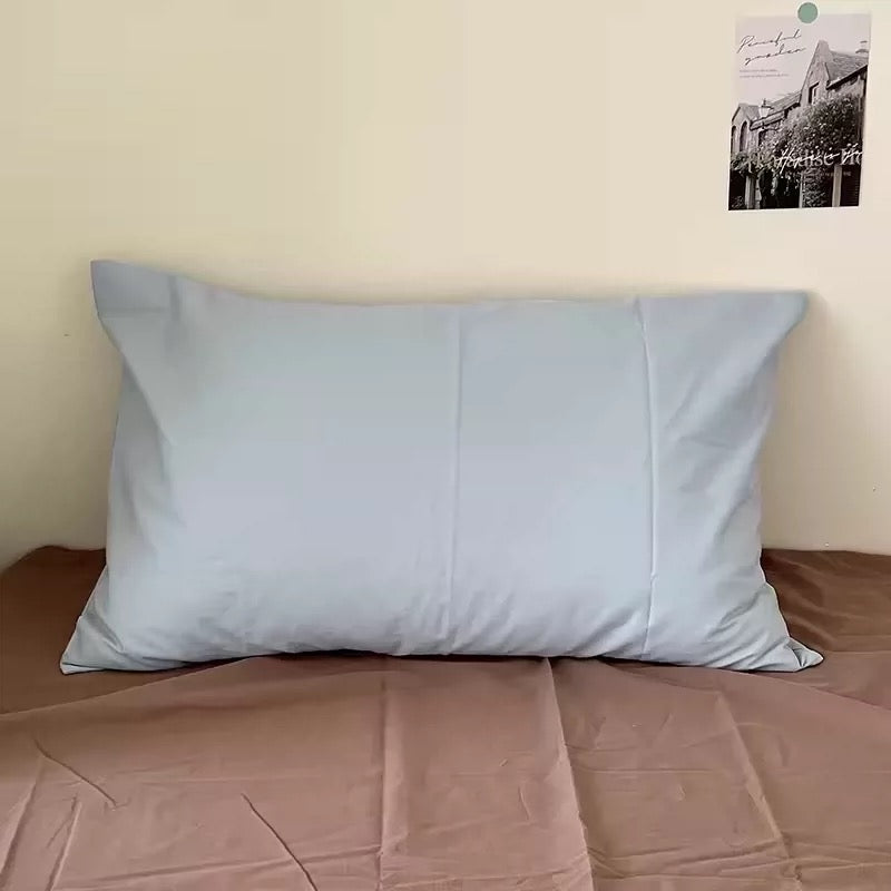 Single solid powder blue cotton pillowcase on a bed.