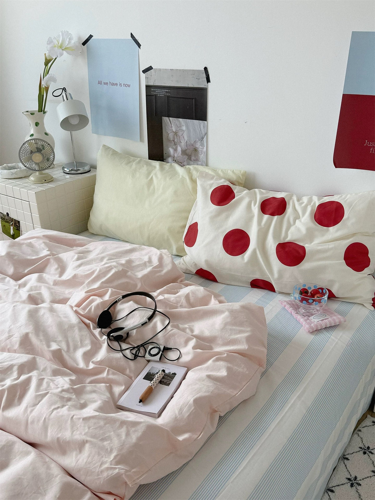 A pale yellow pillow and large red dot pillowcase contrast with plain pink preppy bedding.