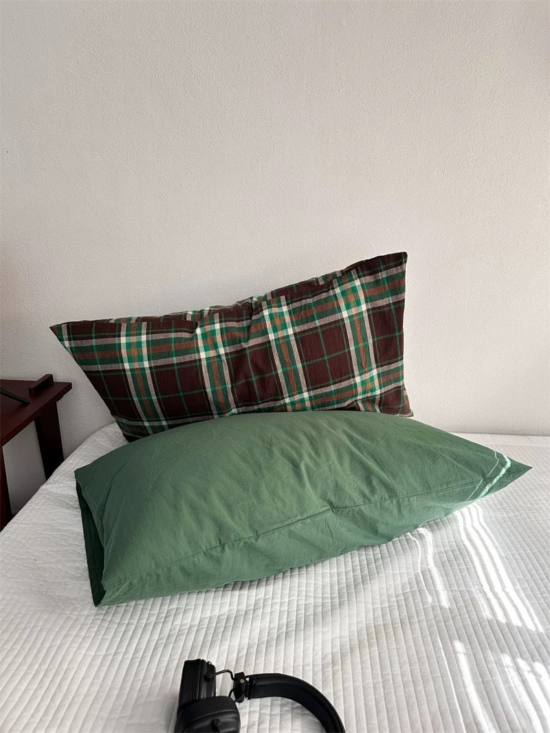 Preppy pillowcase designs pair a plain green pillowcase with a brown plaid design behind it.