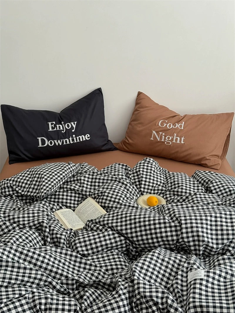 Checkered duvet cover on a bed with pillows and a small table in the background.