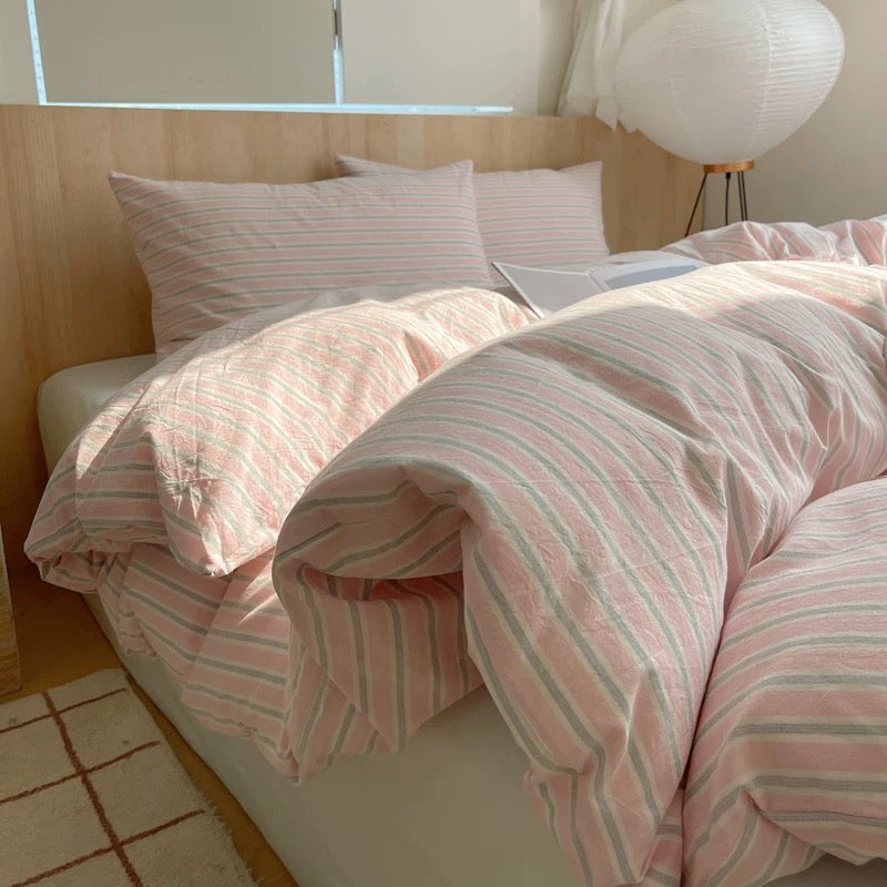 Bed with pink and white striped bedding in a bright room.