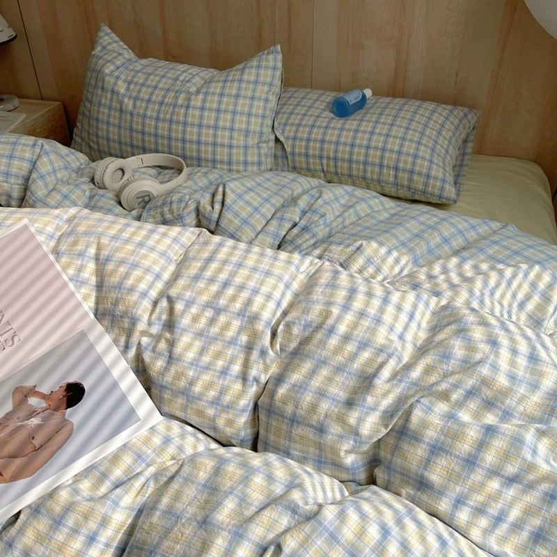 Bed with checkered bedding and pillows, with a magazine on top.