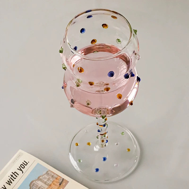 Decorative wine glass with colorful dots on a white background