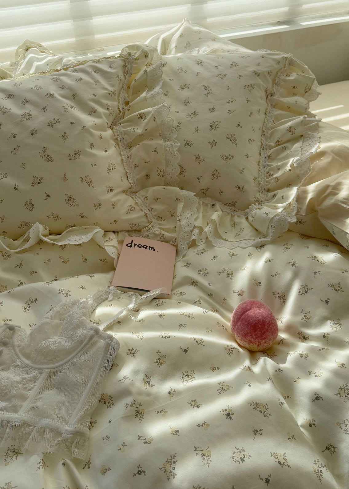 Floral bedding with a pink notebook and peach on a bed